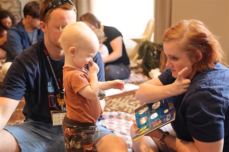  Parents reading a book in American Sign Language with their toddler. 